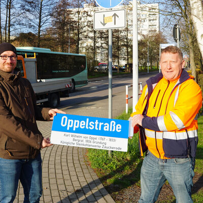 Silvio Messerschmidt (l.), Amtsleiter des Stadtbauamtes und Bauhofleiter Jens Straube (r.) mit dem ersten der angebrachten neuen Straßenzusatzschilder an der Oppelstraße. 
