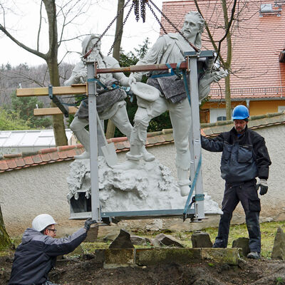 Ein Kran lässt die Skulptur von Rotkopf Görg Ende März 2023 wieder an den angestammten Platz im Schlosspark einschweben.