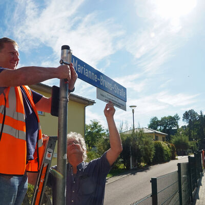 Bauhofleiter Jens Straube (l.) und Bauhofmitarbeiter Wilhelm Dachtler bringen das neue Straßenschild an der Marianne-Bruns-Straße in Deuben an.