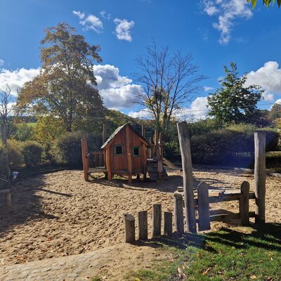 Sandspielfl&auml;che mit einem kleinen Holzhaus in der Mitte