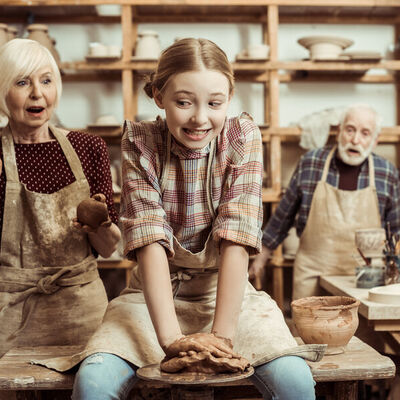Grandmother and grandfather with granddaughter making pottery at workshop