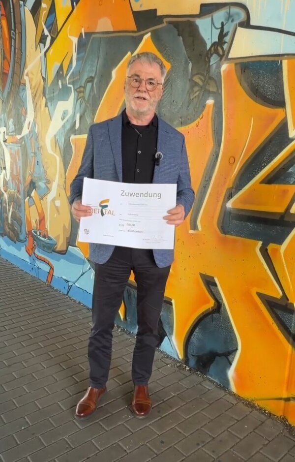 Oberb�rgermeister Uwe Rumberg mit einem symbolischen Scheck �ber 500 Euro vor der mit Graffitikunst gestalteten Bahnunterf�hrung Dresdner/Tharandter Stra�e