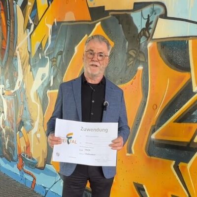 Oberb&uuml;rgermeister Uwe Rumberg mit einem symbolischen Scheck &uuml;ber 500 Euro vor der mit Graffitikunst gestalteten Bahnunterf&uuml;hrung Dresdner/Tharandter Stra&szlig;e
