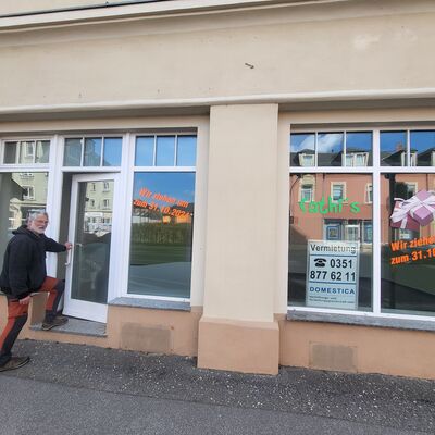 Ein Mann betritt ein leeres Ladengesch&auml;ft. Im Vordergrund ist ein asphaltierter Gehweg.