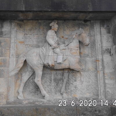 Das sanierungsbed&uuml;rftige Reiterrelief aus Sandstein zeigt K&ouml;nig Albert auf einem Pferd. Das rechte Bein des Pferdes ist abgebrochen. Die Ohren des Pferdes sind nicht mehr vorhanden. Das Bein des Reiters ist abgebrochen. Das Relief ist insgesamt stark besch&auml;digt.